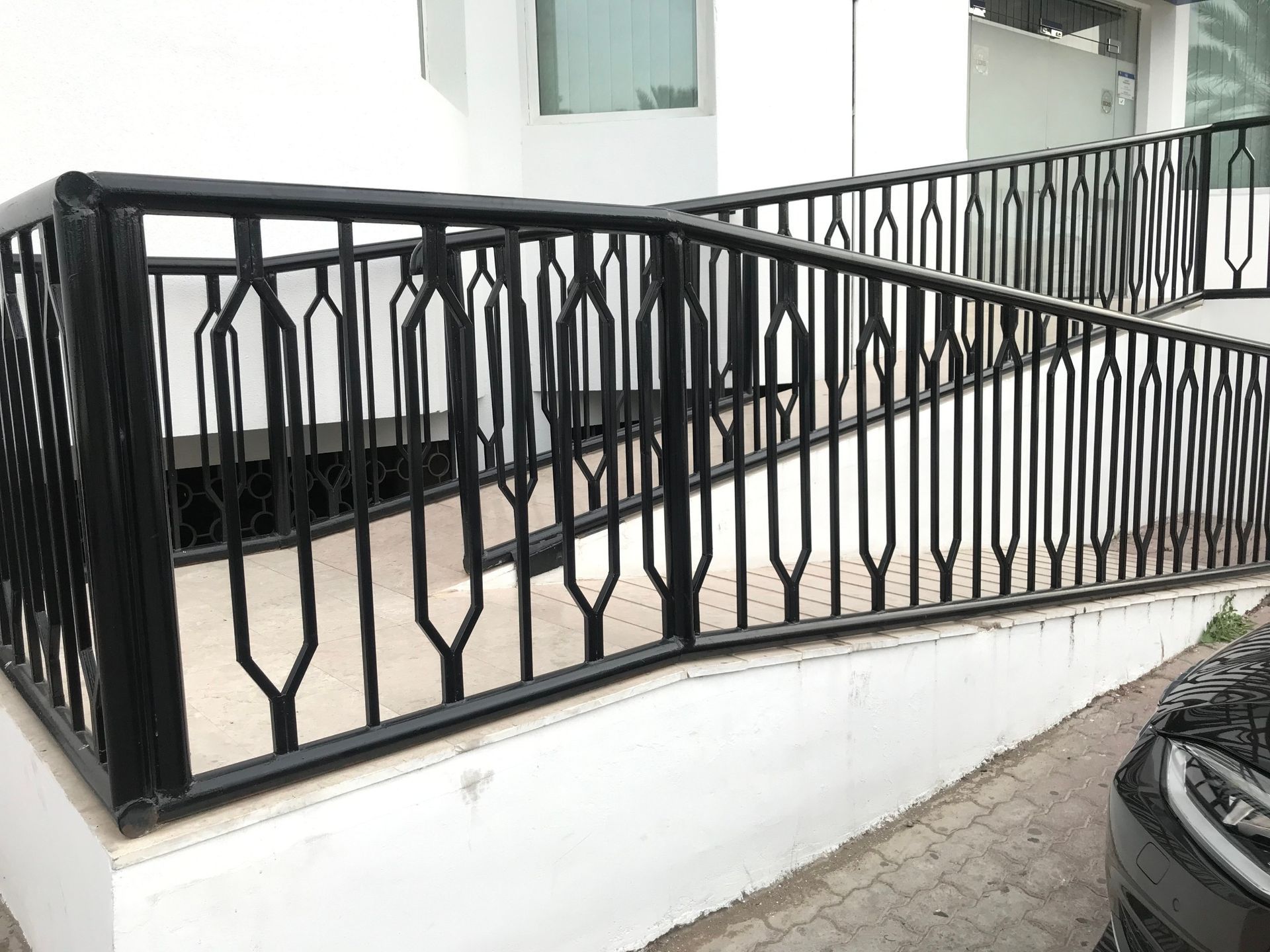 Un coche está aparcado junto a una rampa con barandilla negra.