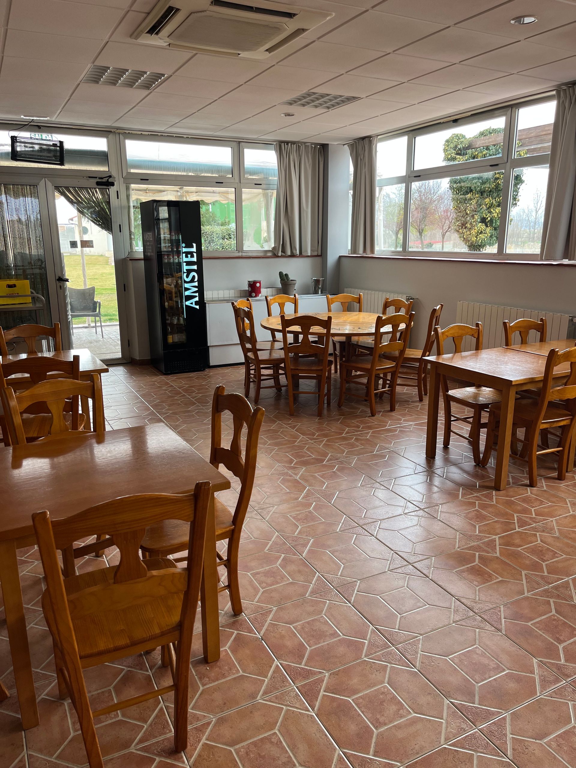 Un restaurante con mesas y sillas y una nevera que dice Amstel.