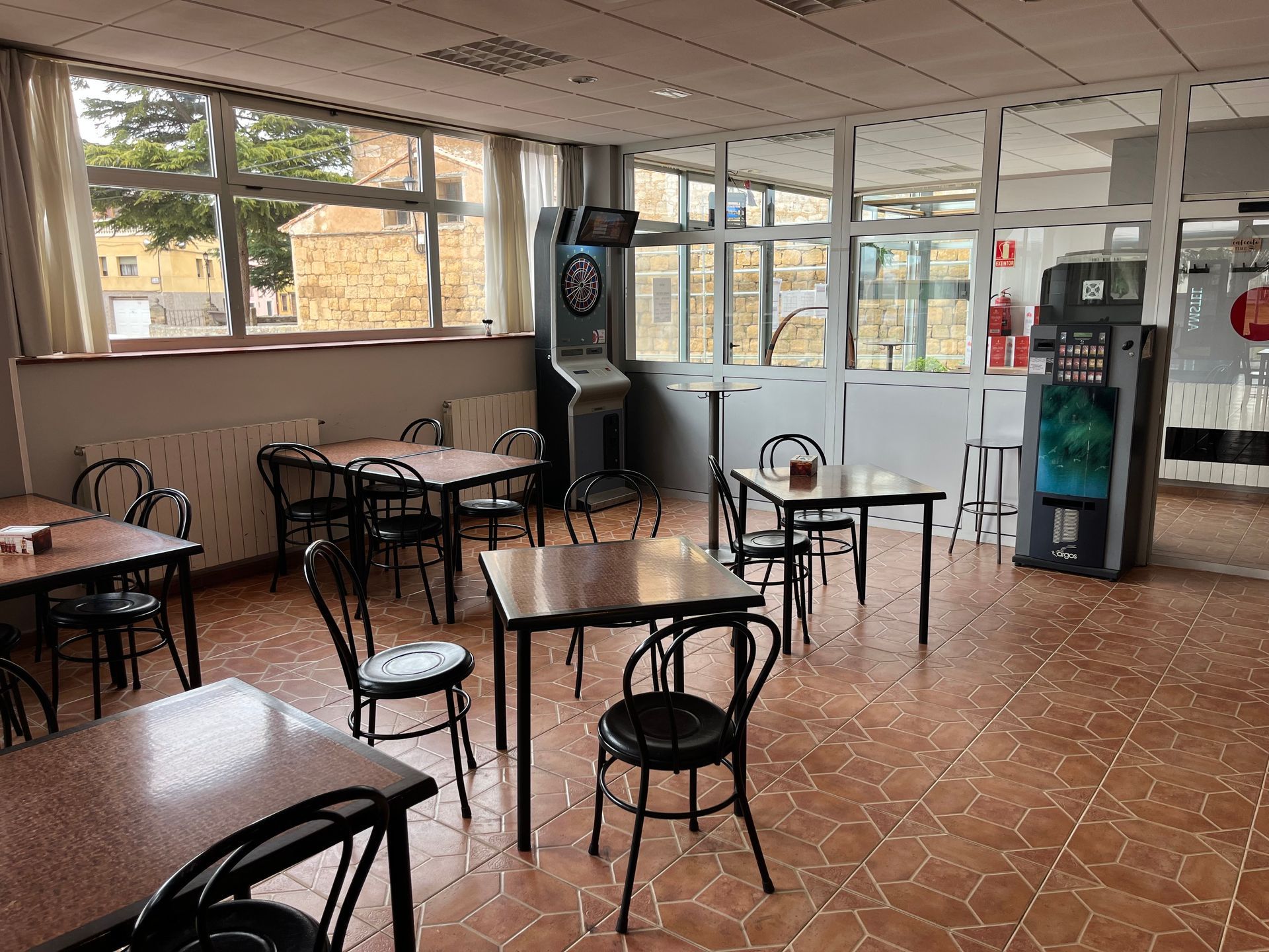 Un comedor con mesas y sillas y un tablero de dardos.