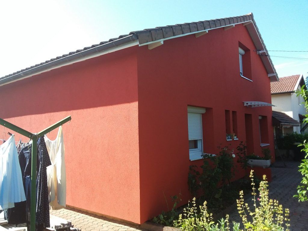 Maison peinte en rouge vue de trois quart après travaux
