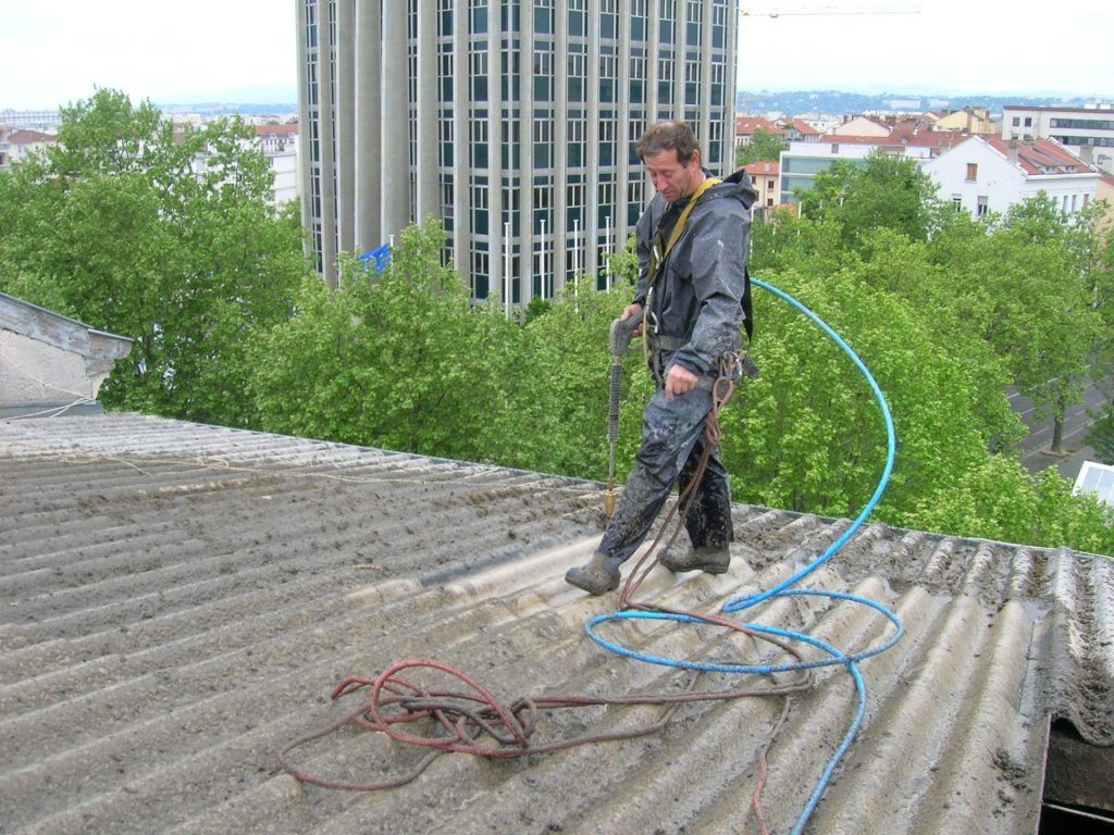 Homme debout sur un toit avec un jet d'eau à haute pression