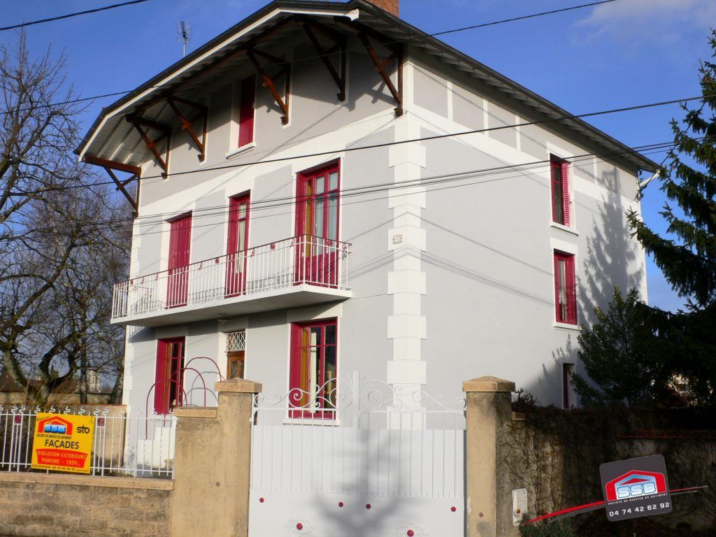 Maison grise à étages avec volets rouges