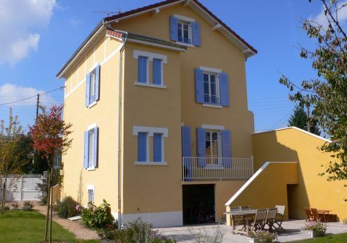 Maison peinte en jaune avec volets bleus