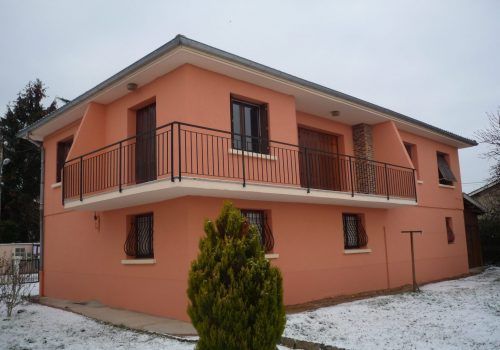 Maison peinte en rouge vue de trois quart après travaux
