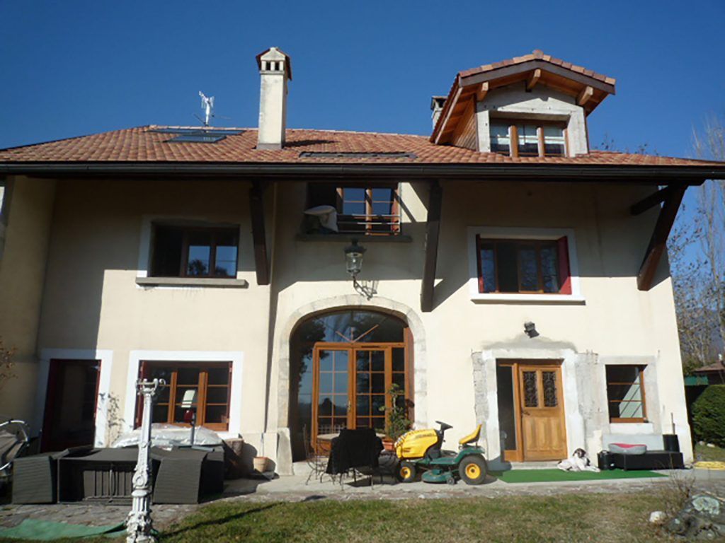 Façade d'une maison à étage aux murs blancs et pierres apparentes