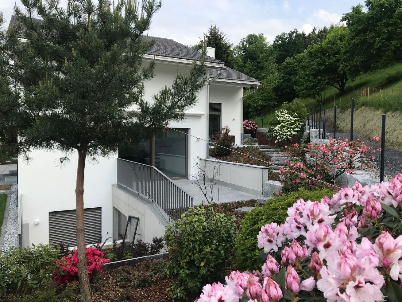 A white house with pink flowers in front of it