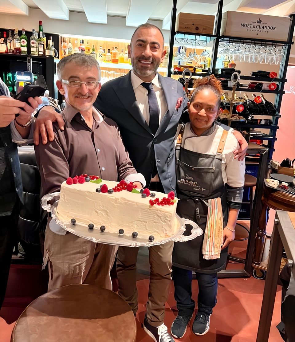 Un groupe de personnes pose pour une photo tout en tenant un gâteau.