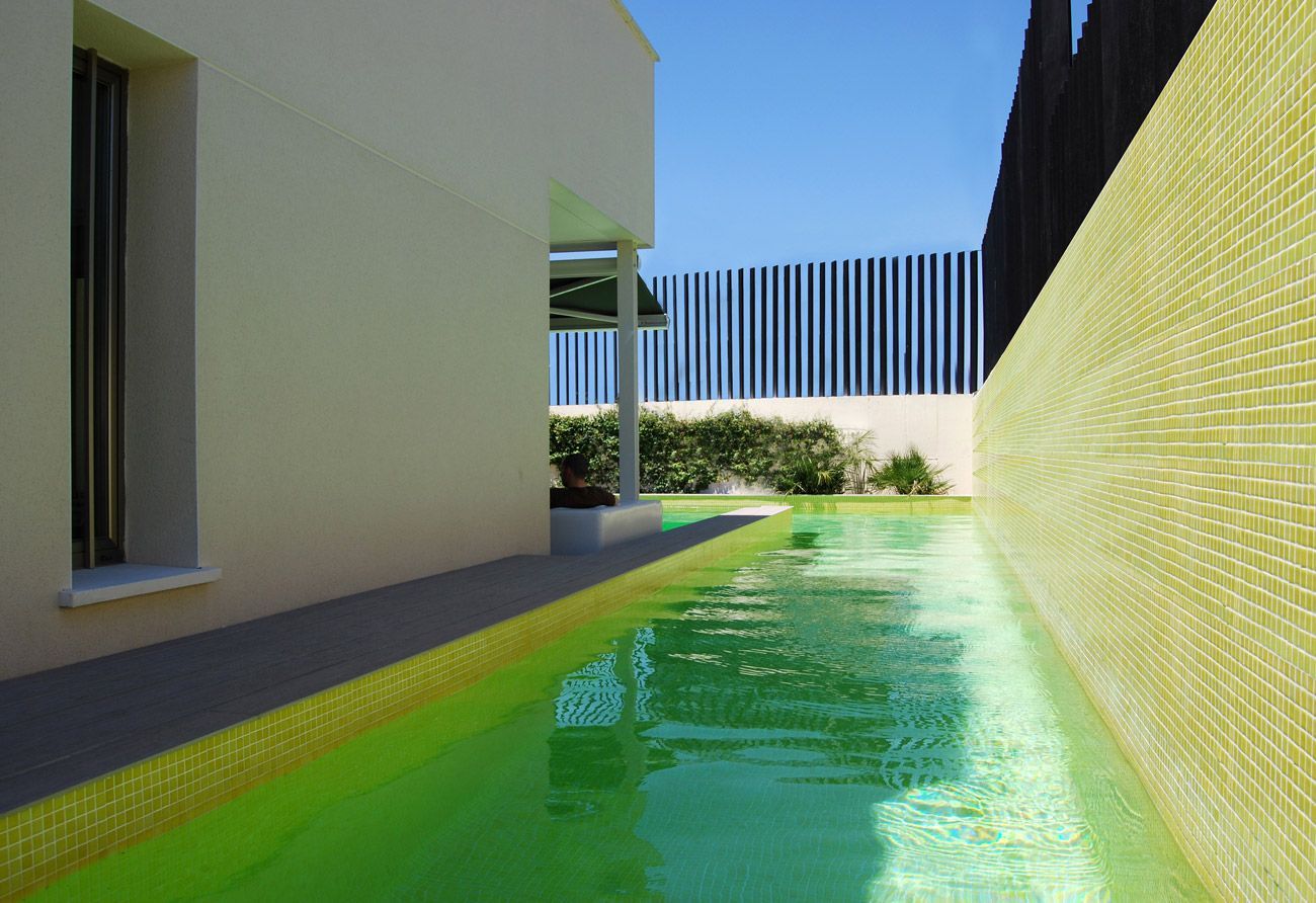 Una piscina estrecha está rodeada por una pared amarilla.