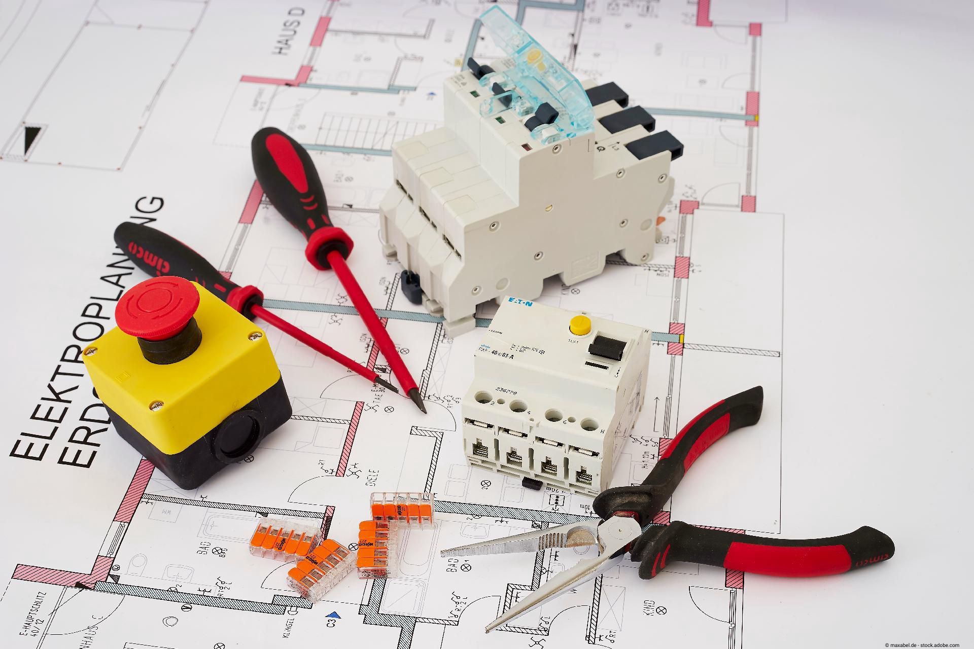 Elektrowerkzeuge und Sicherungskomponenten auf Bauplan, darunter Schraubendreher, Zangen und Schalter.