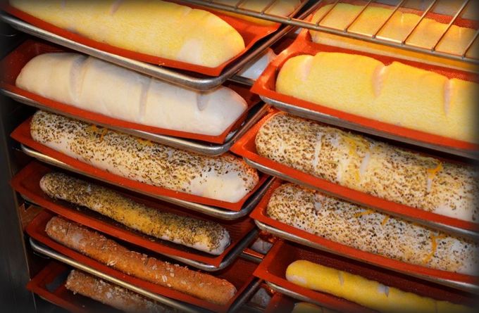Bandejas apiladas de panes en una panadería o estante de fermentación.