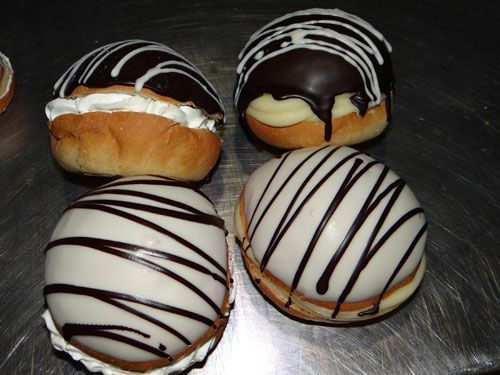Cuatro rosquillas glaseadas con chocolate y glaseado blanco en una bandeja de metal.