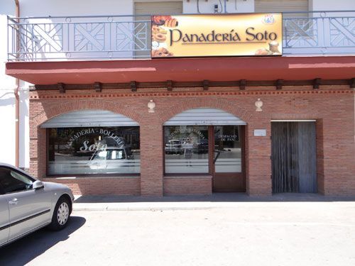 Fachada de ladrillo con un letrero amarillo de “Panadería Soto” y un coche aparcado delante.