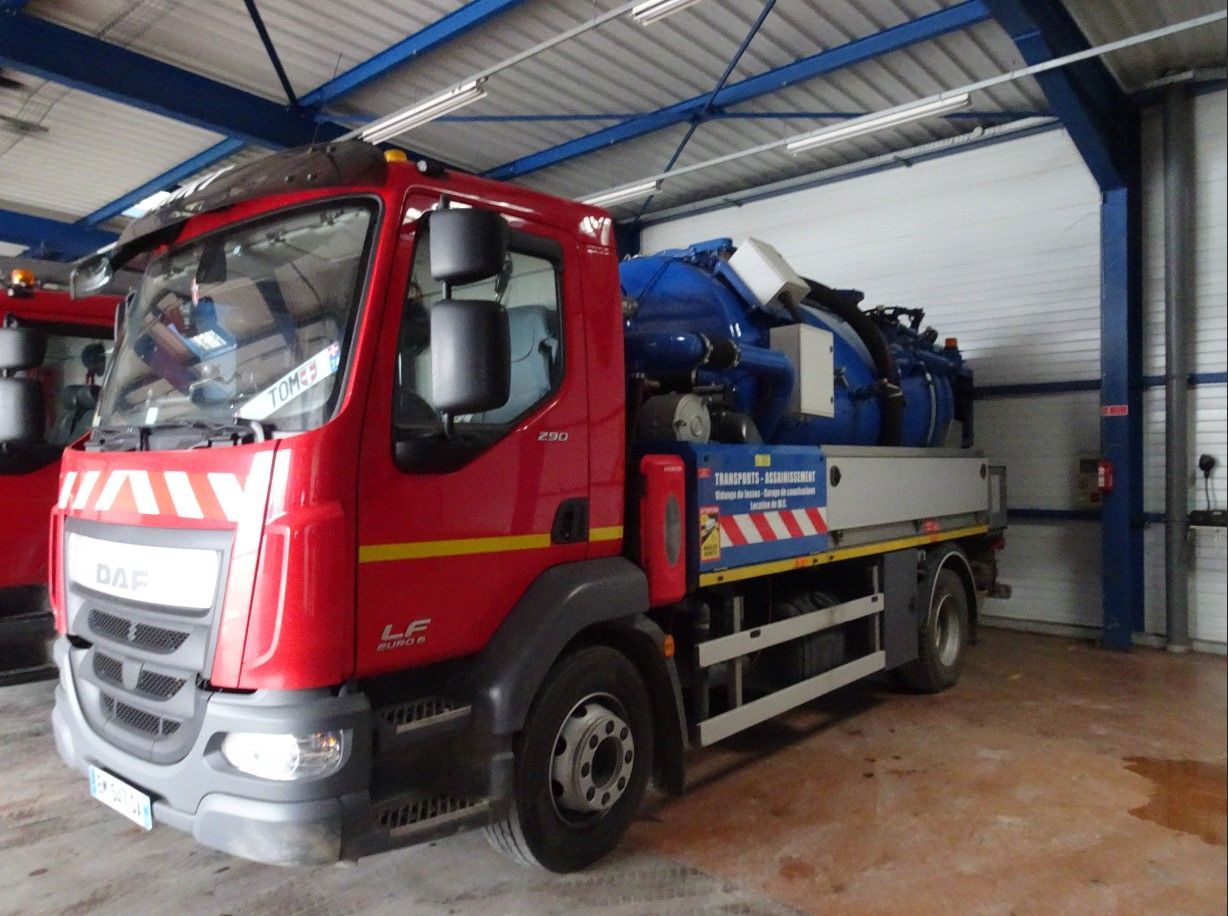 Un camion d'intervention d'urgence rouge est stationné à l'intérieur d'un entrepôt aux poutres de soutien en acier bleu.