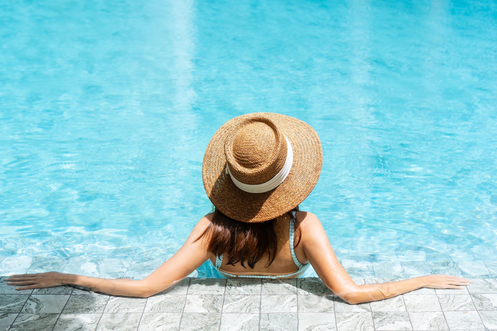 Une personne de dos qui se détend au bord de sa piscine