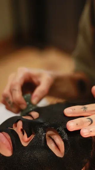 Una persona se aplica una máscara negra en la cara.