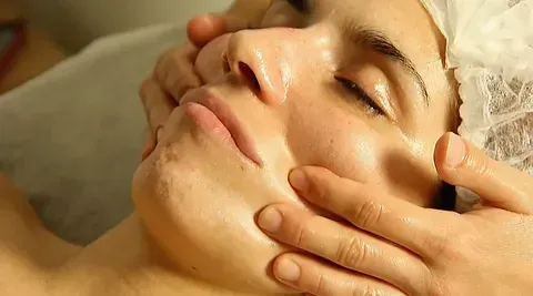 Una mujer está recibiendo un masaje facial en un spa.