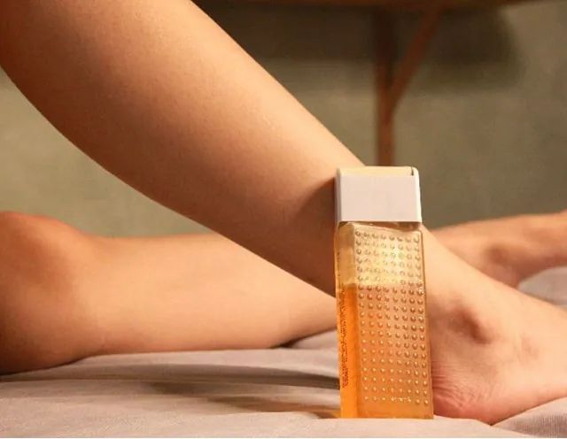 La pierna de una mujer con una botella de loción encima.