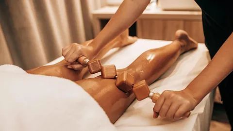 Una mujer recibe un masaje de madera en su pierna en un spa.