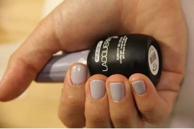 Una mujer sostiene una botella de esmalte de uñas.
