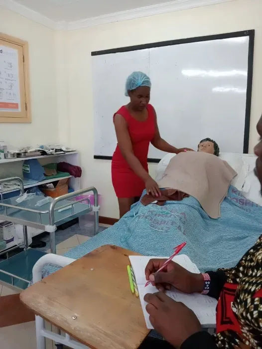 A woman in a red dress is standing next to a patient in a hospital bed