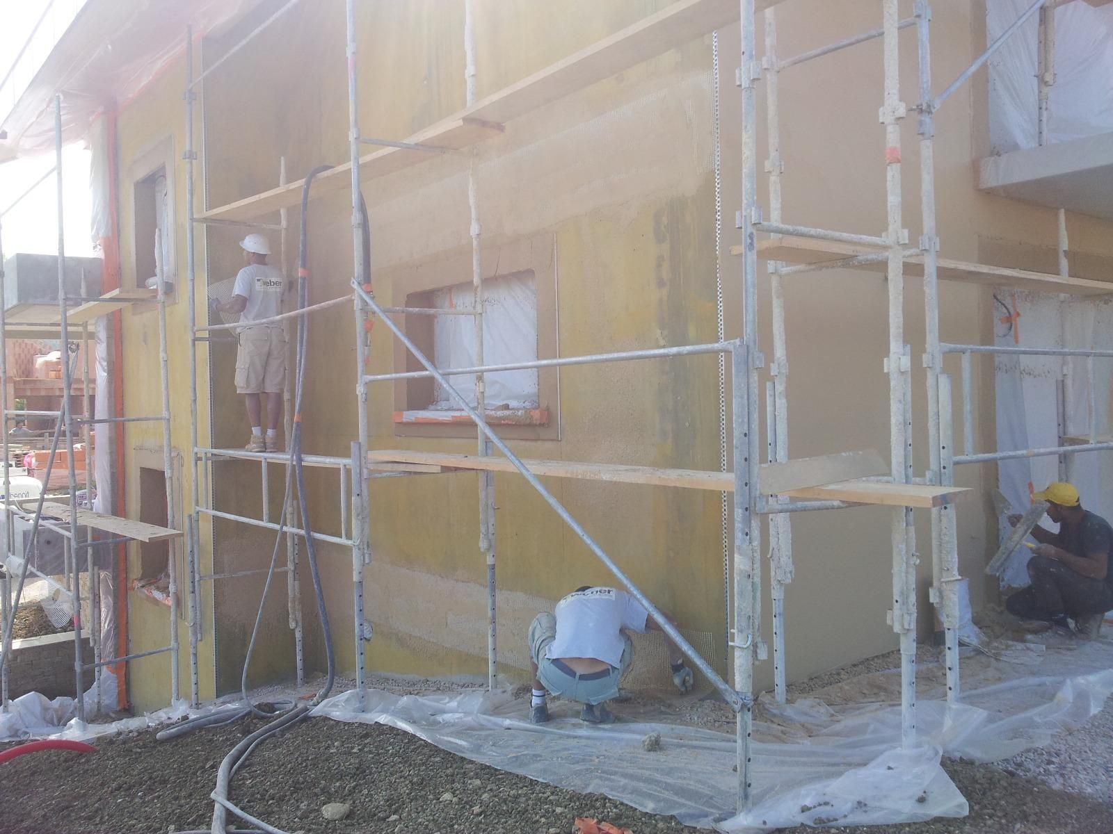 Deux ouvriers sur un échafaudage isolent la façade d'une maison