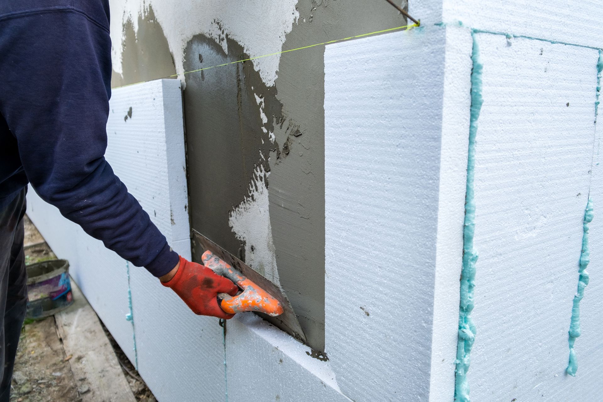 Un ouvrier pose du polystyrène isolant sur la façade d'une maison