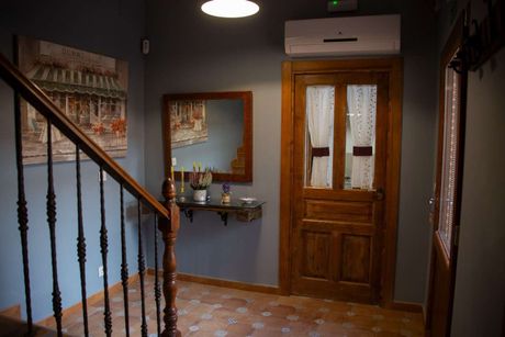 Acogedor salón rústico con chimenea de piedra, sofá de mimbre, vigas de madera y ventana soleada.