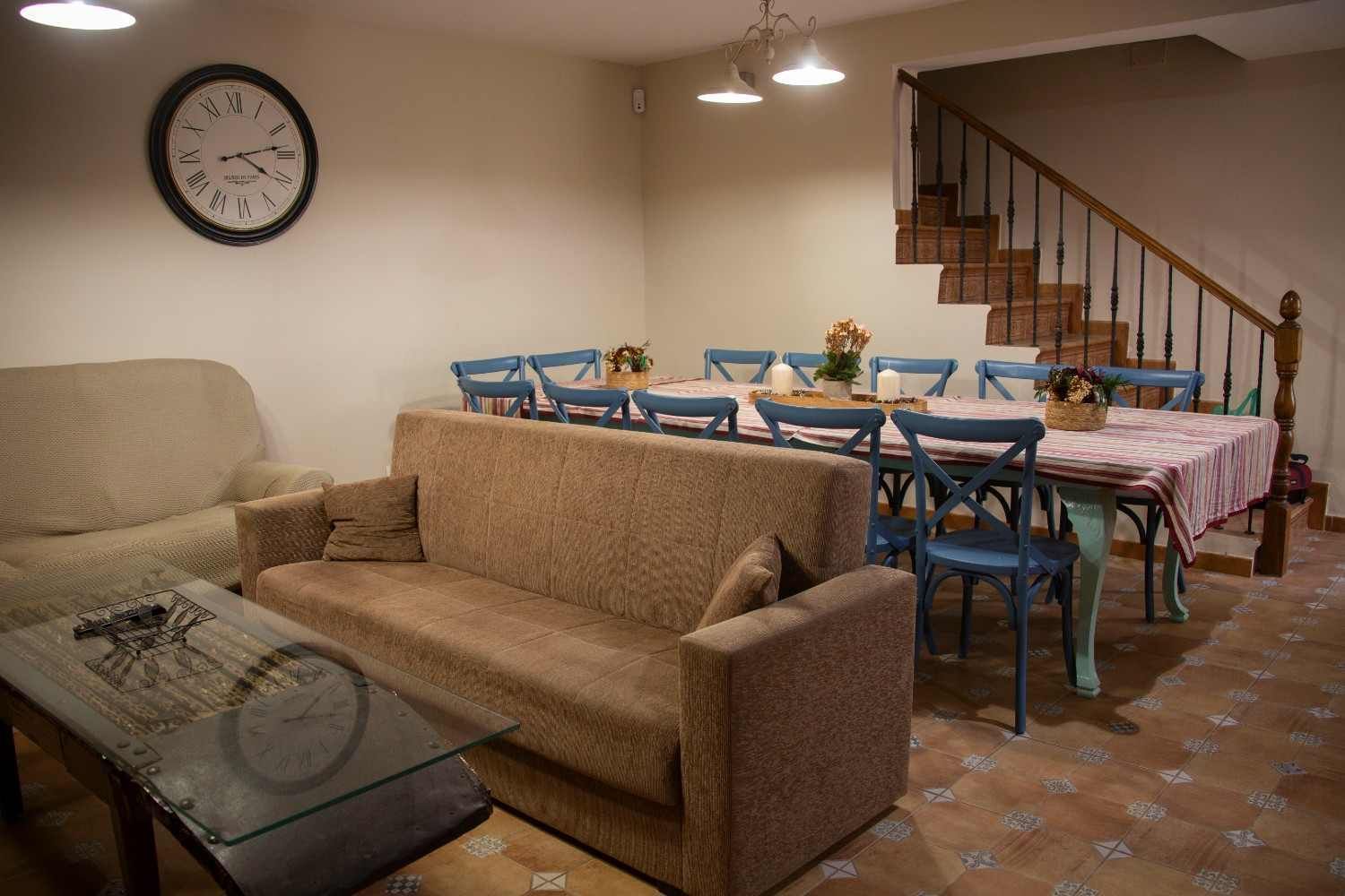 Acogedor dormitorio rústico con vigas de madera, una cama blanca con manta verde y cálida luz natural.