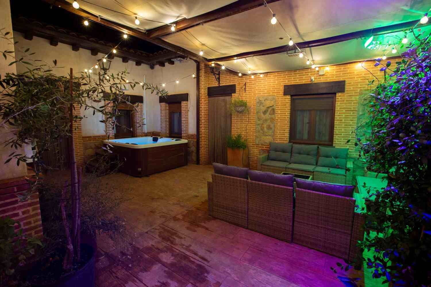 Comedor rústico con mesa de madera, bancos, plantas en macetas y luz solar que entra por dos ventanas.