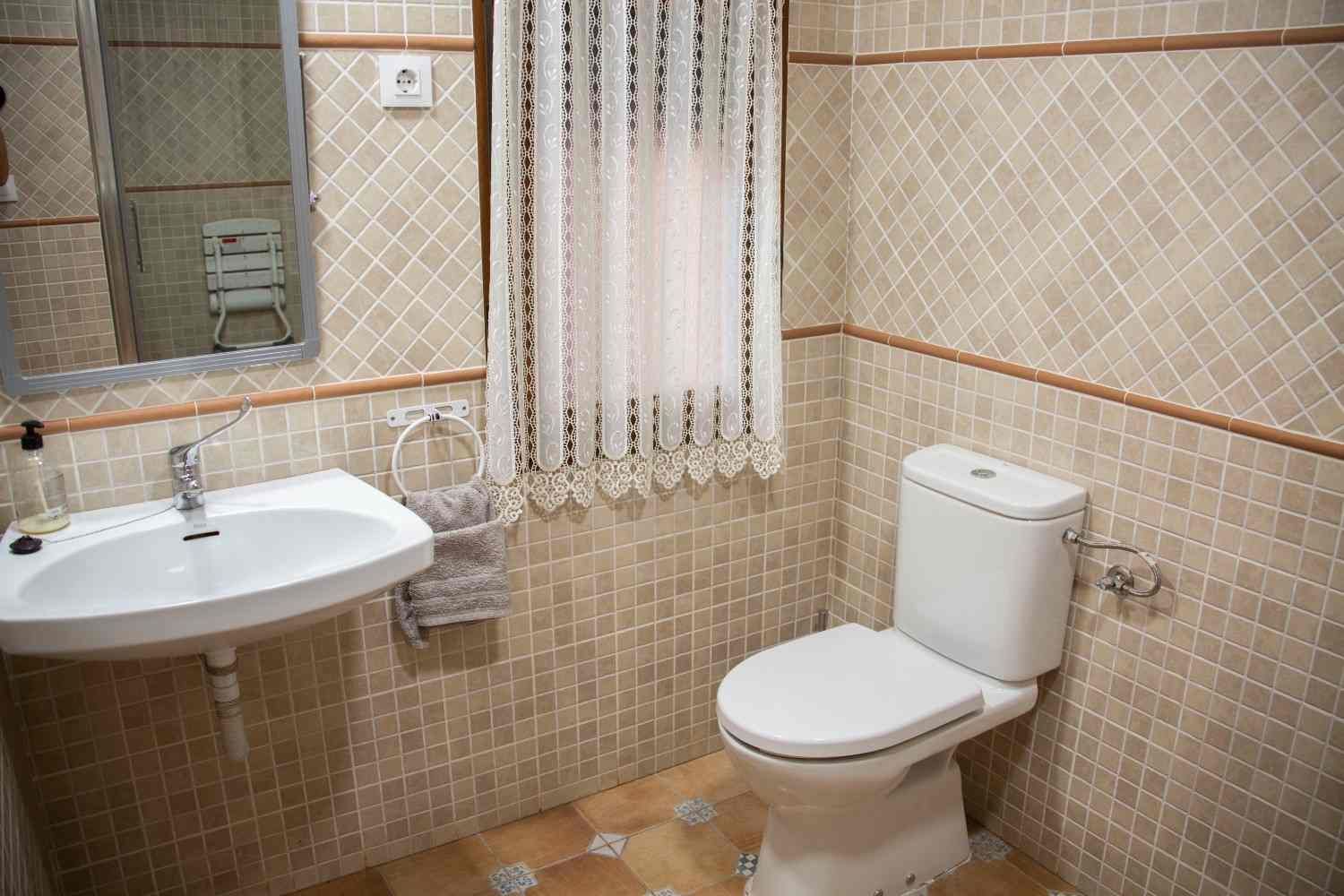Baño pequeño de color beige con lavabo, inodoro, espejo y cortina de ducha.