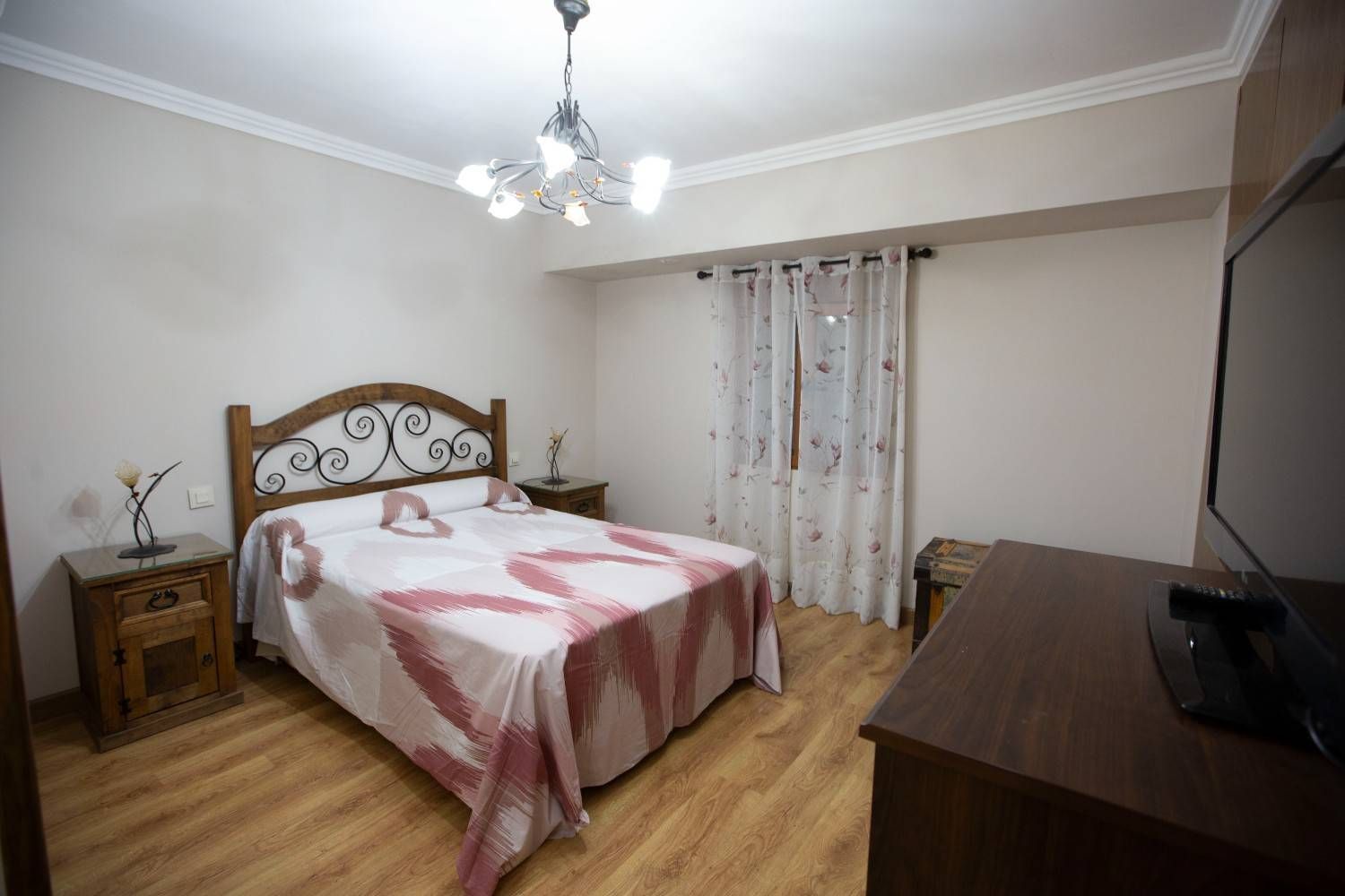 Dormitorio con cama, mesita de noche, cómoda y cortinas en una habitación de color beige.