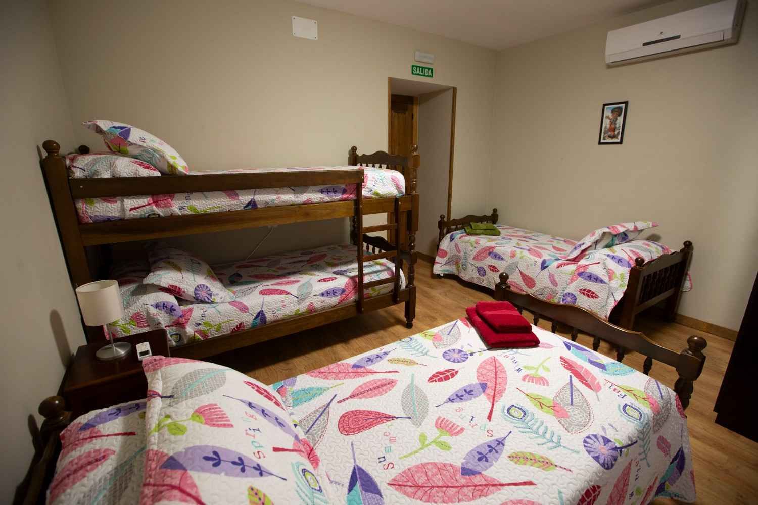 Acogedor dormitorio rústico con vigas de madera, una cama blanca con manta verde y cálida luz natural.