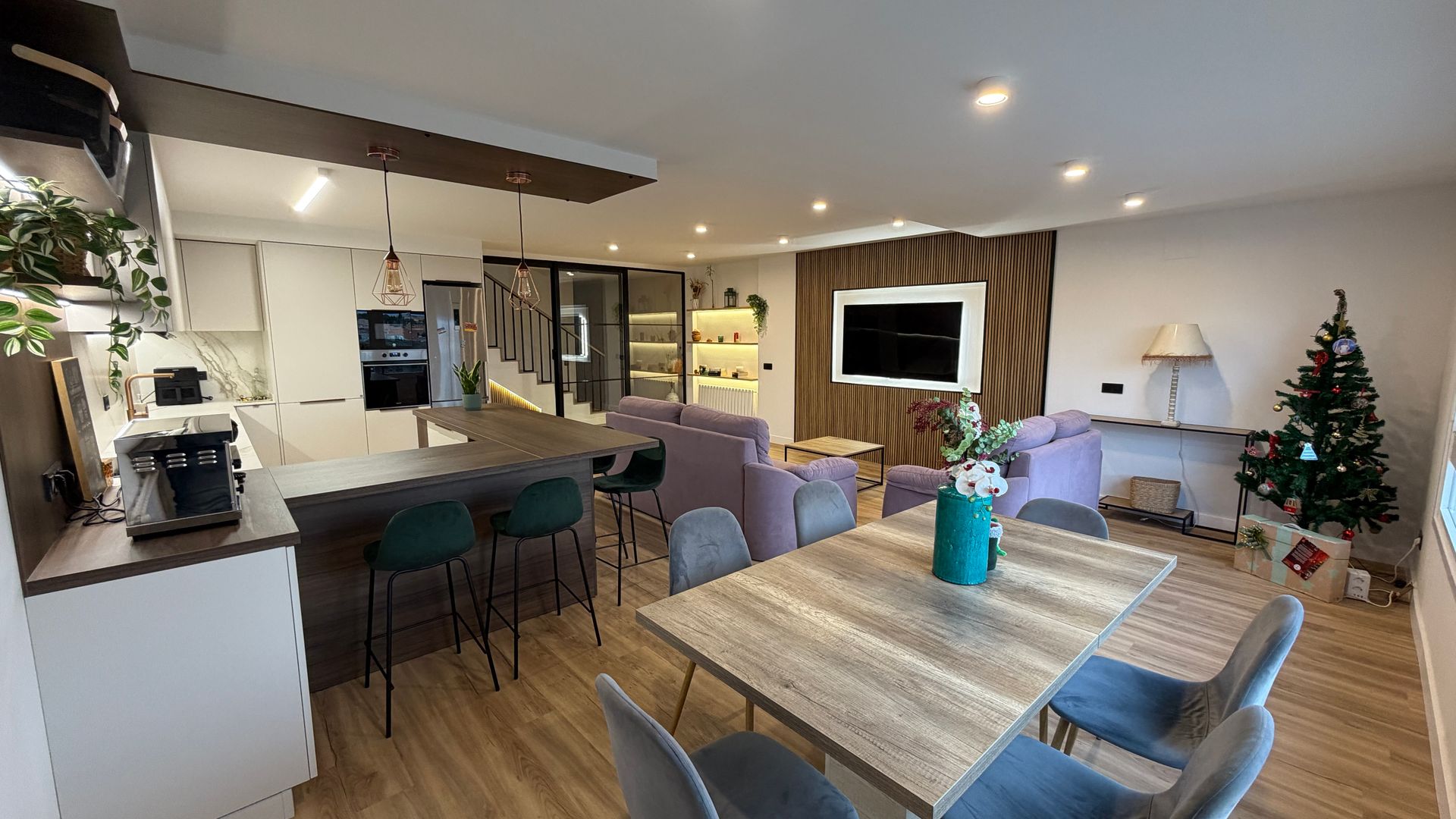Espacio habitable de concepto abierto con isla de cocina, mesa de comedor, zona de estar y árbol de Navidad.