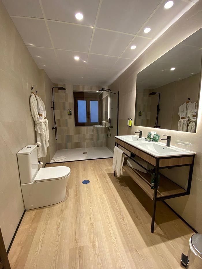 Baño moderno con inodoro, ducha, tocador y combinación de colores neutros.