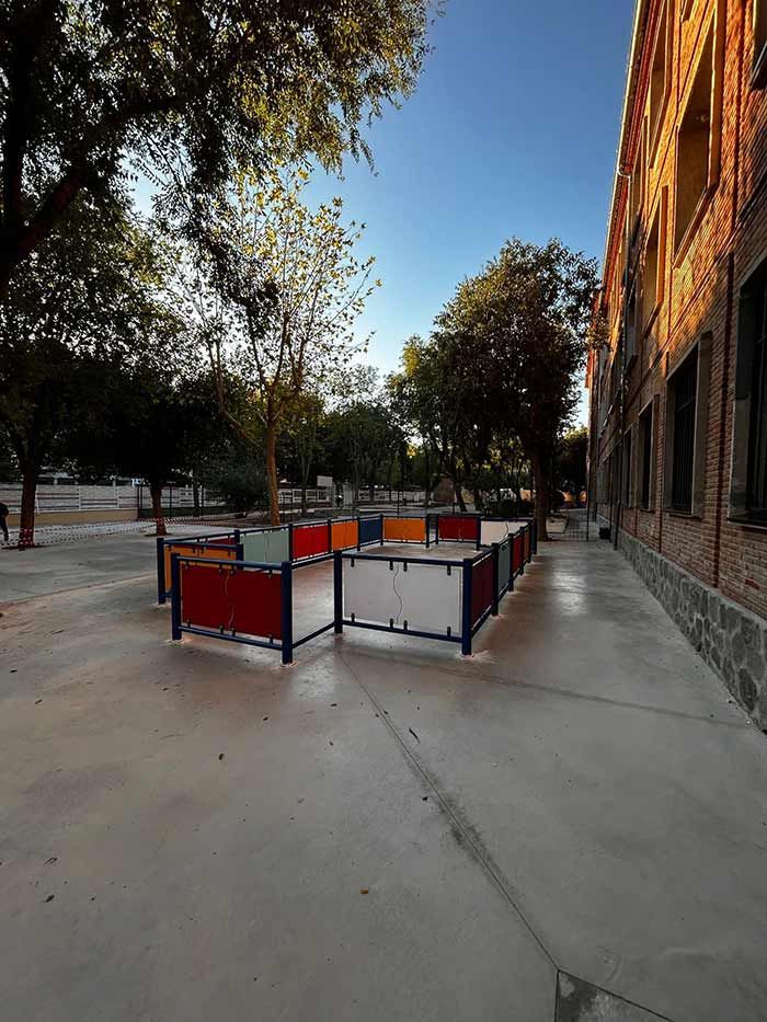 Espacio exterior con paneles de colores y un edificio de ladrillo bajo un cielo soleado.