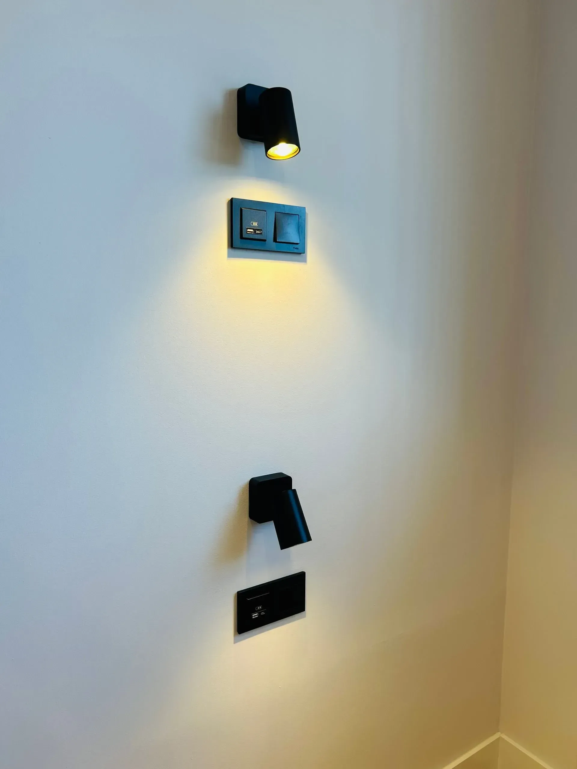 Dos focos negros montados en una pared con interruptores de luz negros a juego.