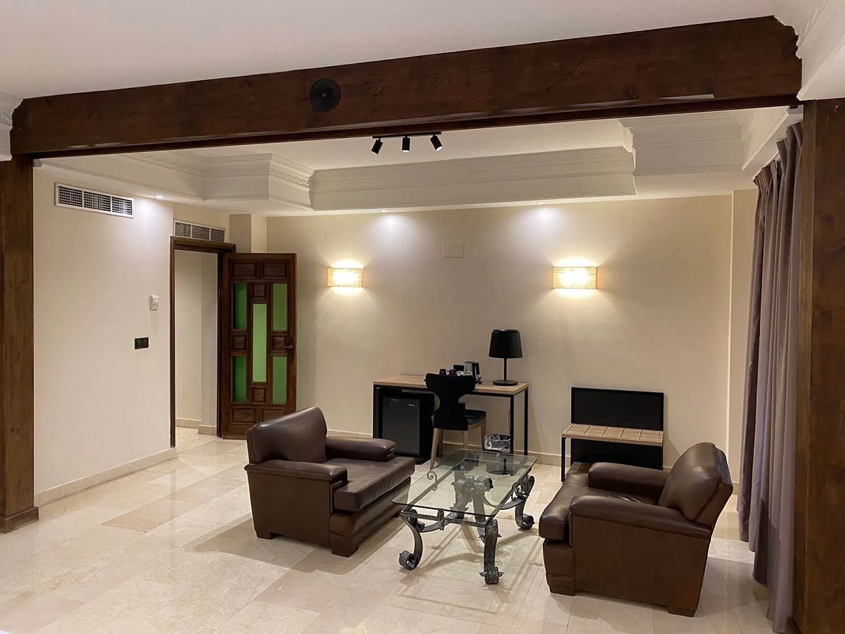 Sala de estar con sillones de cuero marrón, mesa de vidrio y detalles de madera.