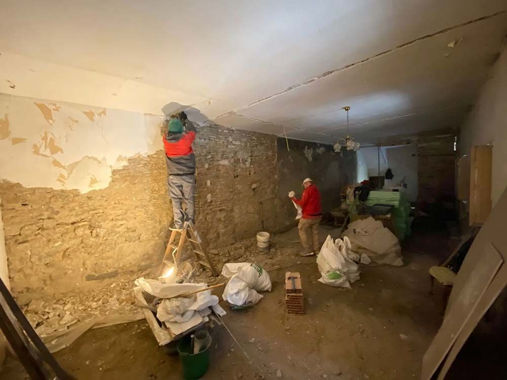 Hombres quitando yeso de una pared de una habitación durante una renovación.