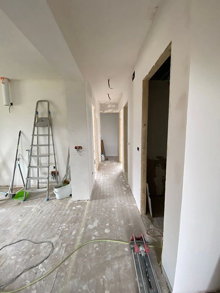 Vista interior de un pasillo en reforma con herramientas y suelo a la vista.