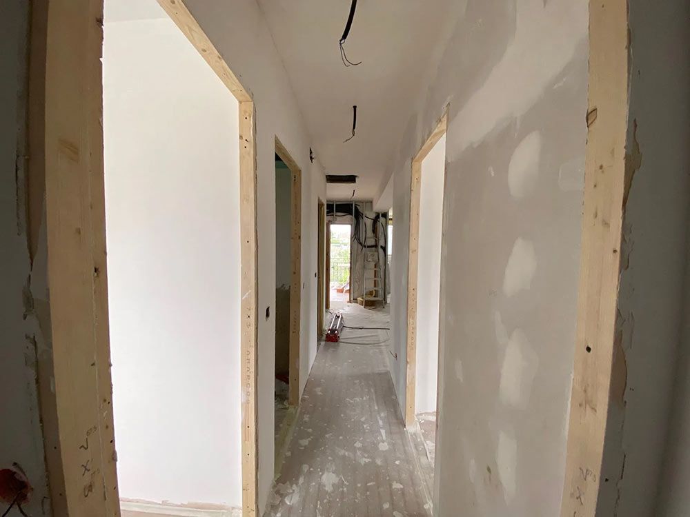 Pasillo en construcción con paneles de yeso y marcos de puertas de madera.