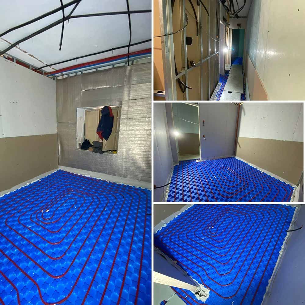 Instalación de sistema de calefacción por suelo radiante: paneles aislantes azules con tubos rojos/negros en las habitaciones.