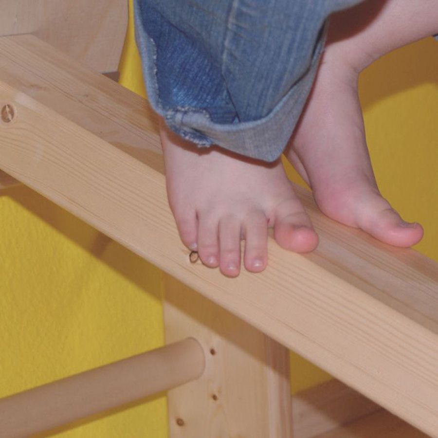 Kinderfüße balancieren über einen Holm