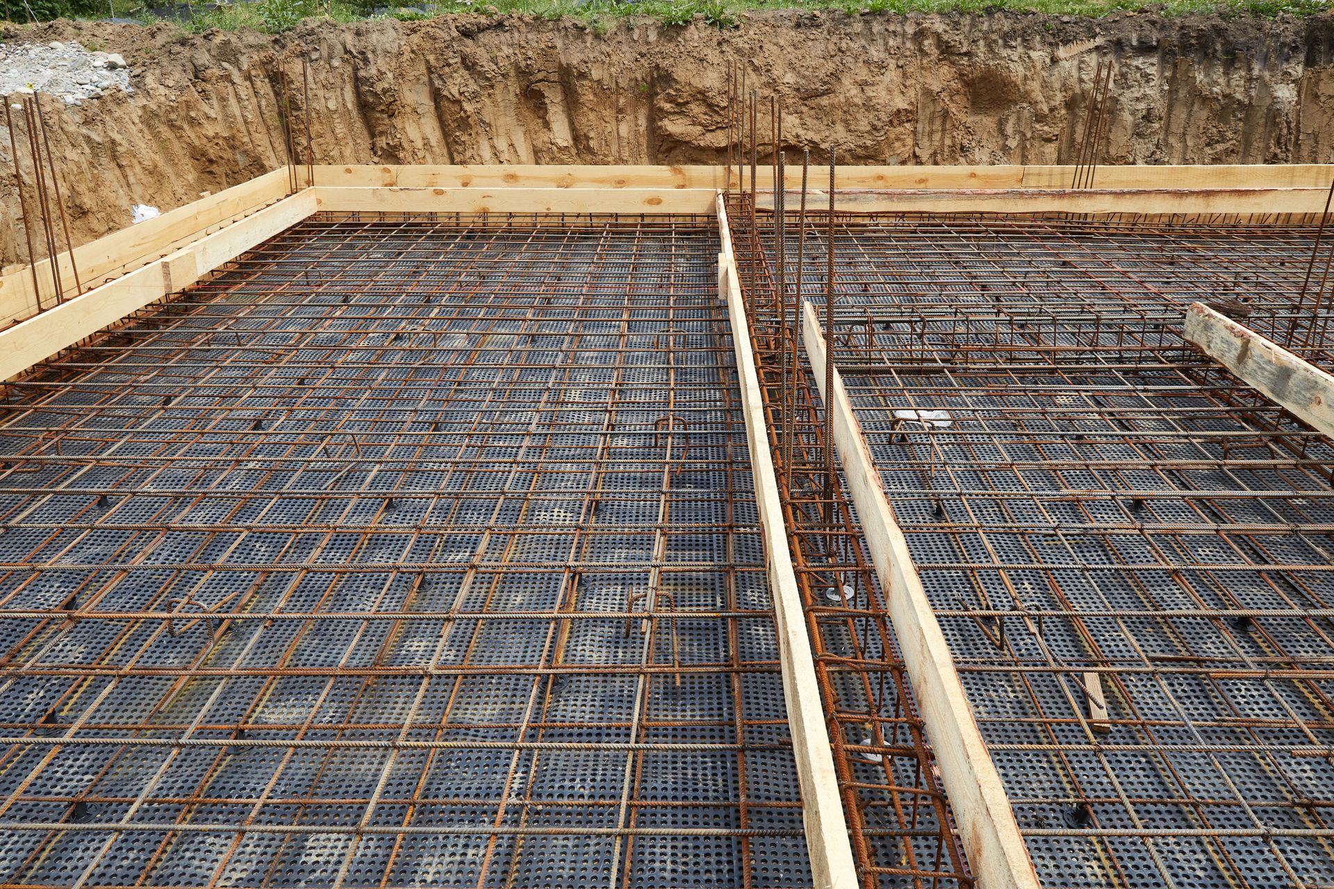 Armature métallique et coffrage en bois pour une fondation en béton sur un chantier de construction.