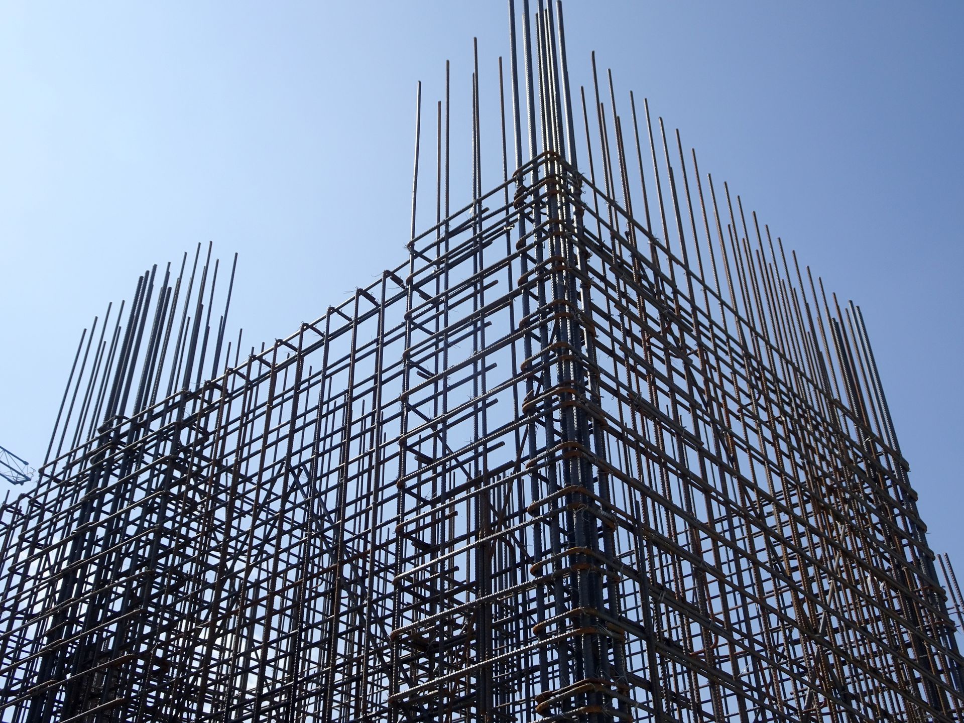 Charpente métallique d'un bâtiment en construction se détachant sur un ciel bleu clair.