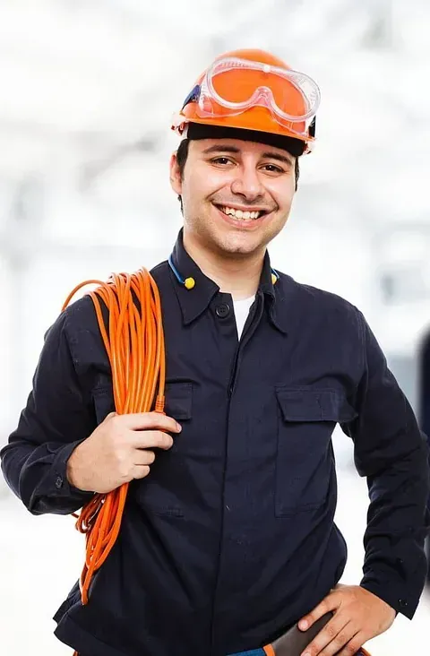 Un hombre que lleva casco y gafas protectoras sostiene un cordón naranja.