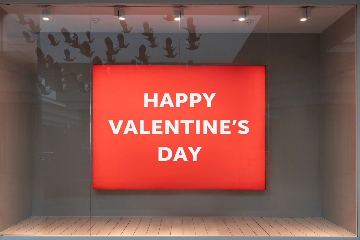 Cadre lumineux Happy Valentine's Day blanc sur fond rouge dans une vitrine