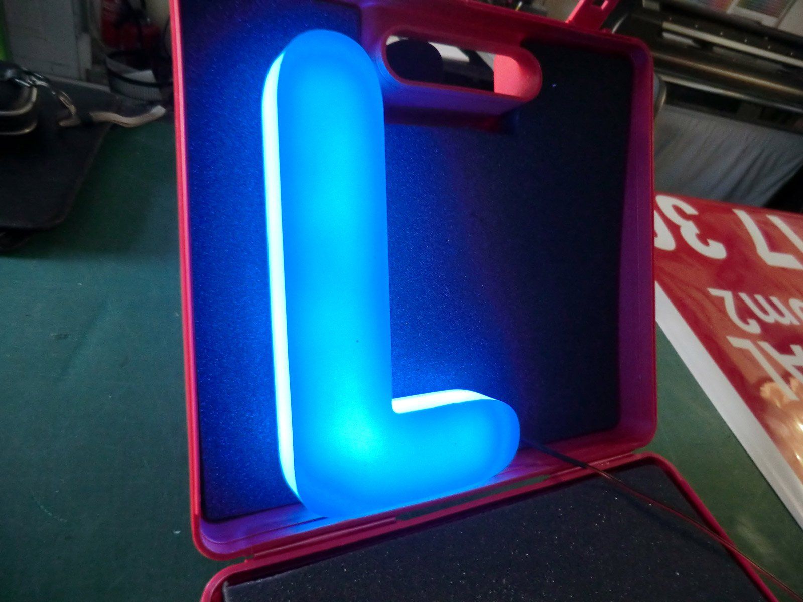 Enseigne lumineuse avec la lettre L bleue dans une boîte rouge et noire à l'interieur