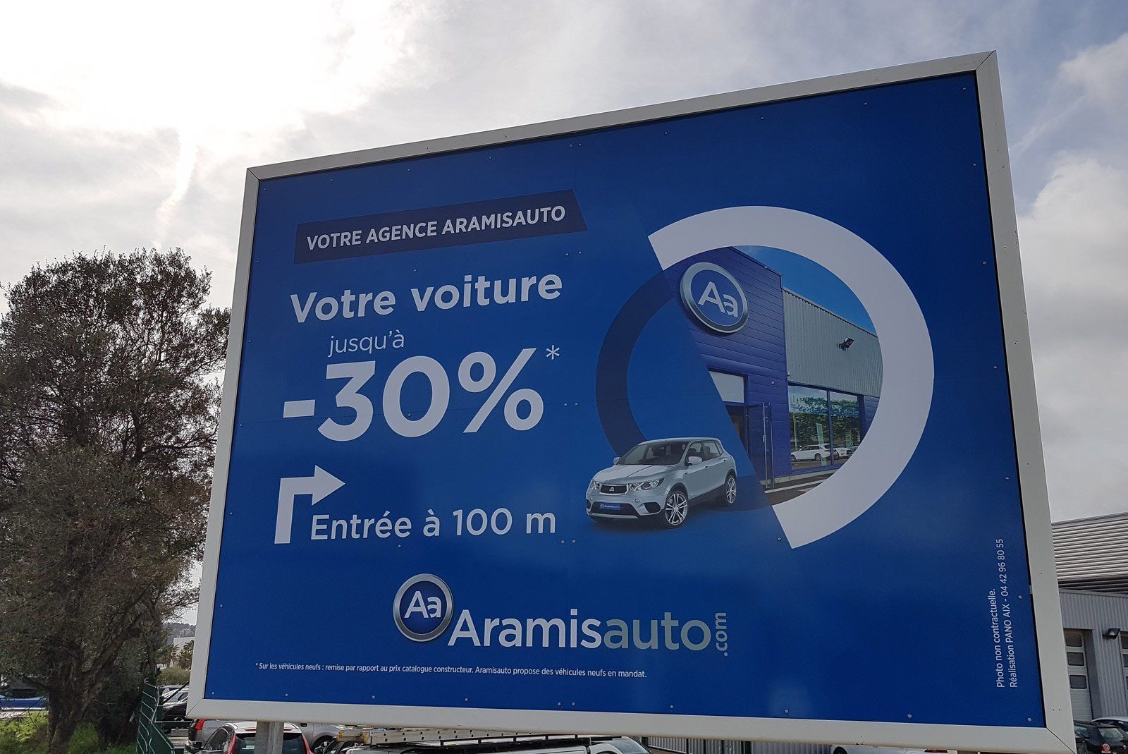 Panneau publicitaire bleu et blanc pour l'agence AramisAuto