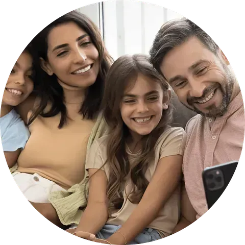 Familia sonriendo y mirando el teléfono. Mujer con camisa color canela, hombre con camisa rosa.