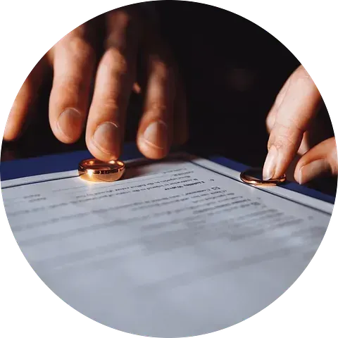 Manos colocando anillos de boda en los papeles de divorcio.